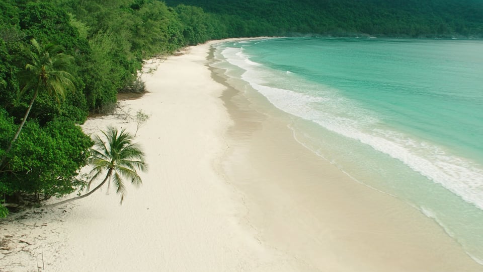 Aerial photograph of an empty white-sand beach curving along the Koh Rong coast