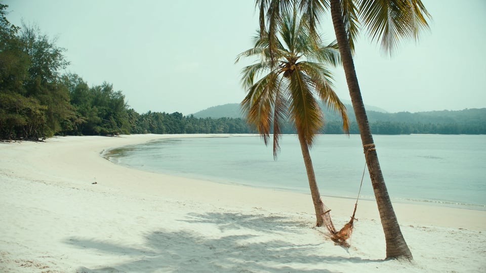 Quiet crescent bay with palms and a hammock on Koh Rong Sanloem